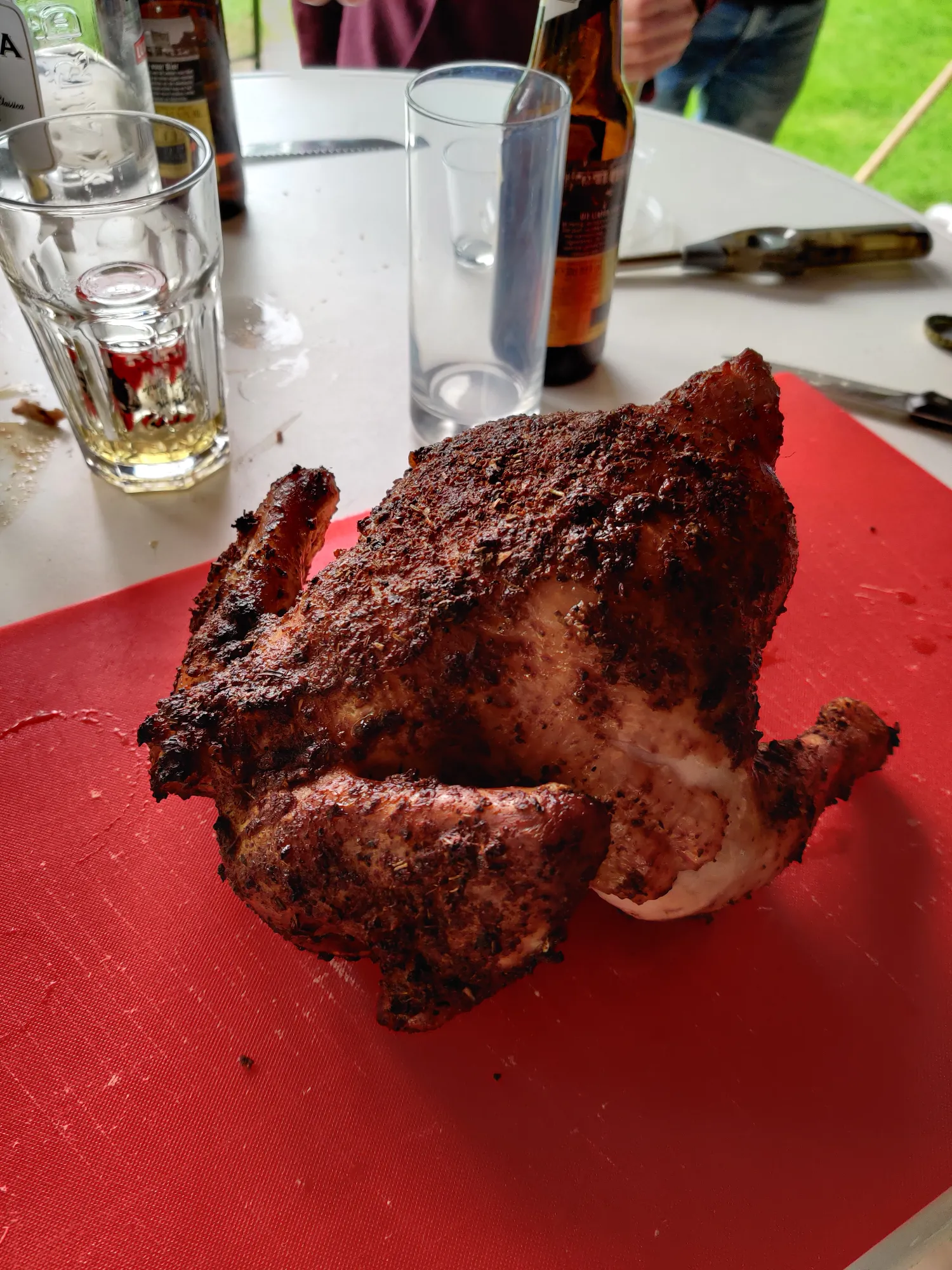 Hele kip van de BBQ — donkere knapperige buitenkant, klaar om te snijden