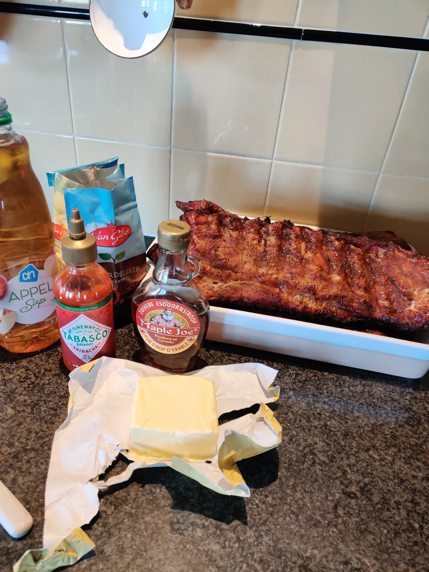 Ingrediënten voor lak: appelsap, maple syrup, Tabasco en boter naast gerookte spareribs